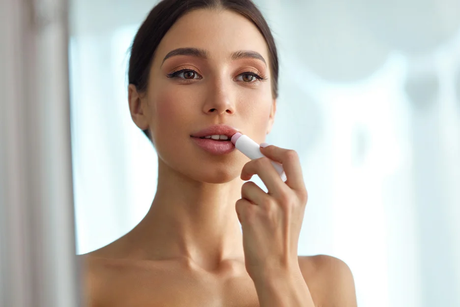 a woman applies lip balm on her lips