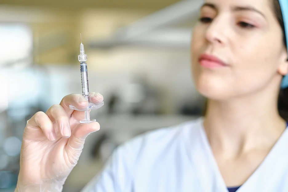 a lip injector holds a syringe filled with lip fillers