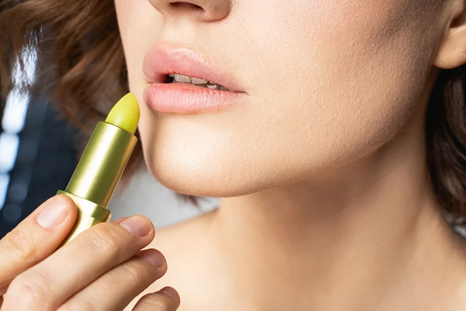a woman applies lip balm on her lips