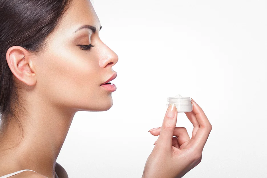 a woman is holding a bottle of arnica cream