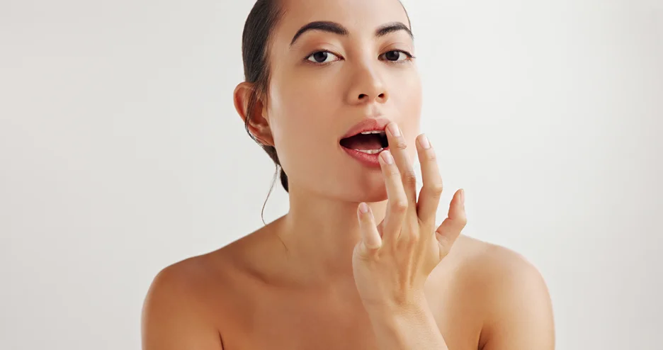 a woman applies lip balm after lip fillers