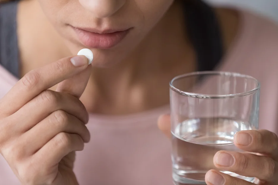 a woman takes a pill to minimize swelling and discomfort after lip fillers